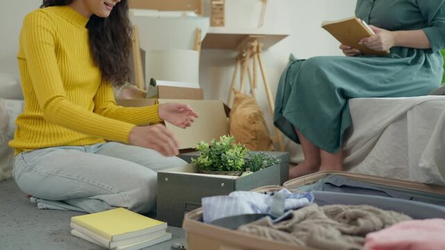 Close up of mother helping daughter organize personal items from moving boxes.