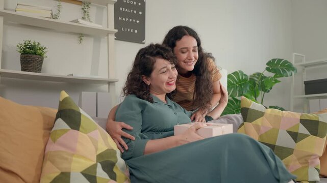 Young adult Latino daughter presenting a gift to her senior mother. 