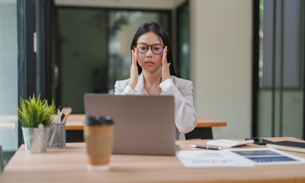 Stressed businesswoman suffering headache working on laptop