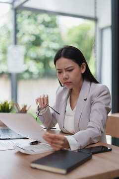 Professional woman analyzing documents feeling stressed in office