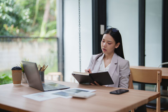 Businesswoman planning strategy reading notebook at office desk