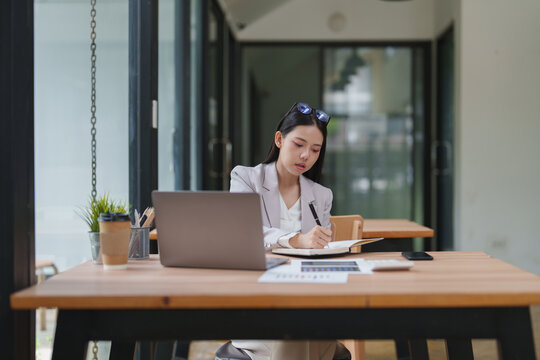 Asian businesswoman writing notes in a modern office
