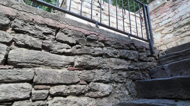 People walk along stone steps in an open area with a railing