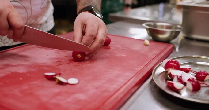 Slicing radish. Preparing vegetable. Chef hand chopping knife on red board raw ingredient for vegan dish. Fresh natural healthy food.
