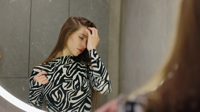 Woman Adjusting Her Hair While Looking in a Mirror