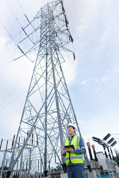Transmission tower inspection captures a lattice pylon while an engineer holds a tablet in an outdoor switchyard with visible insulators.