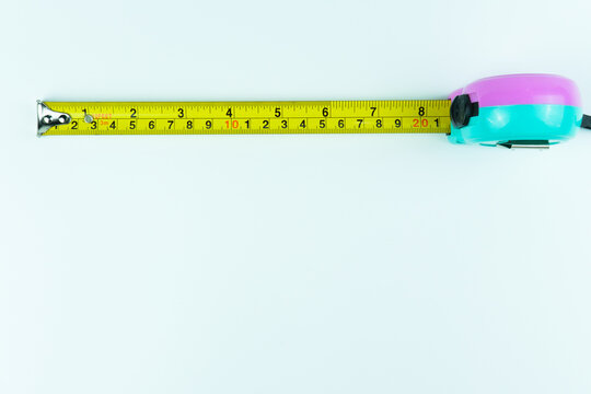 Yellow roll tape measure viewed from the top, positioned at the upper area of clean white background. Ideal for construction visuals, carpentry themes, engineering projects, and DIY concepts.