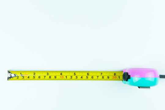 Yellow roll tape measure viewed from the top, positioned at the bottom of clean white background. Ideal for construction visuals, carpentry themes, engineering projects, and DIY concepts.