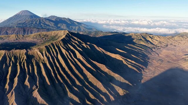 Sunlit volcanic ridges at Mount Bromo with low clouds and long morning shadows