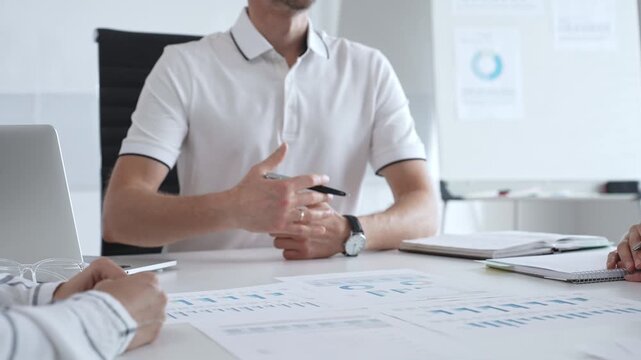 Professional team reviewing financial charts, collaborating intently around conference table in contemporary workspace, sharing insights during strategic planning session