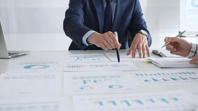 Business people discussing financial reports and marketing charts during corporate meeting, focusing on strategy, planning, data analysis, and teamwork in modern office