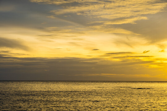 A nature sky panoramic scenic view of a vibrant sunset or sunrise sky with glowing orange and yellow clouds transitioning into deep blue twilight, representing nature beauty, and tranquility at ocean