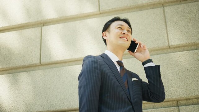 Japanese businessman looking up during a phone call outside an office