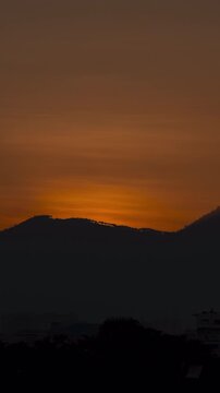 Vertical video - Timelapse of the sun rising behind the mountain silhouette