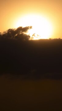 Vertical video - Timelapse of the sun setting behind thick clouds
