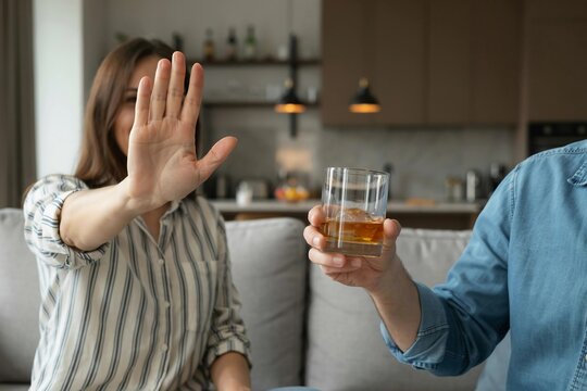 Saying no to alcohol, woman showing stop hand sign to a drink
