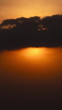 Vertical video - Timelapse of the sun setting behind thick clouds