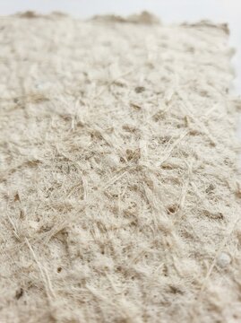 Detailed close up of handmade paper pulp texture featuring prominent fibers and natural elements