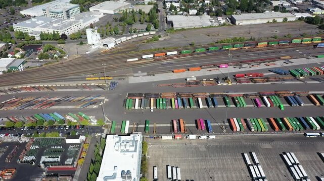 4K aerial drone footage of freight trains and rail yard in Portland, Oregon, USA, with railroad tracks, public transit bus facility, Holgate bridge and industrial transportation infrastructure