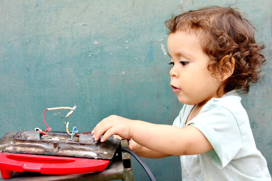 Curious toddler reaching broken appliance.