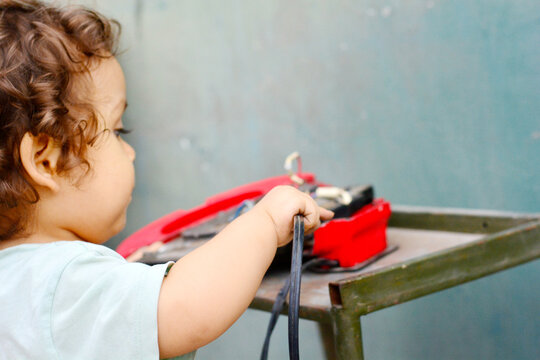Curious toddler reaching broken appliance.
