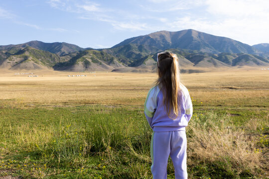 Woman In Sweater Standing On Meadow Path With Mountain Landscape in Xinjiang province China