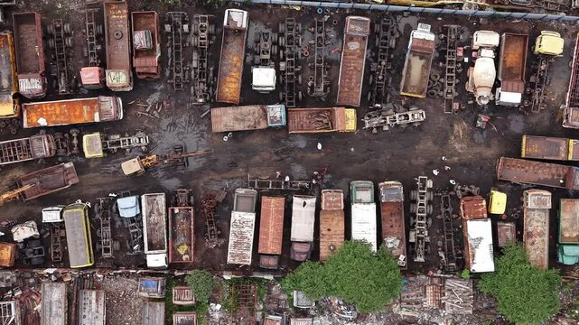 Abandoned rusty trucks lined up at vehicle scrapyard aerial automobile salvage industry