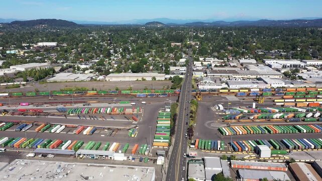 4K aerial drone footage of freight trains and rail yard in Portland, Oregon, USA, with railroad tracks, public transit bus facility, industrial infrastructure and Mount Hood in the background