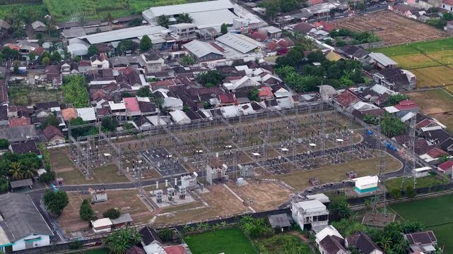 Aerial view of power station surrounded by rural villages. Large grid of transformers at Lumajang