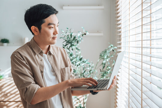 Young Asian man working on laptop at home