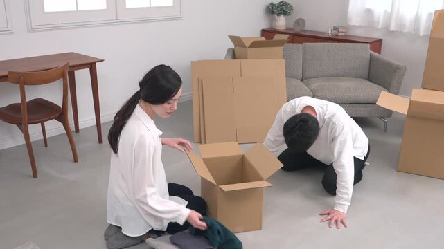 引越し中に土下座で謝る男性と荷物を整理する女性