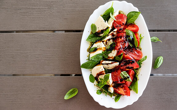 Caprese Salad with Mozzarella, Tomatoes and Basil on White Plate Top View