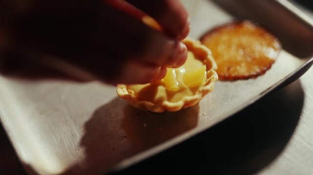 Close-up of a pastry chef filling a tart with lemon curd