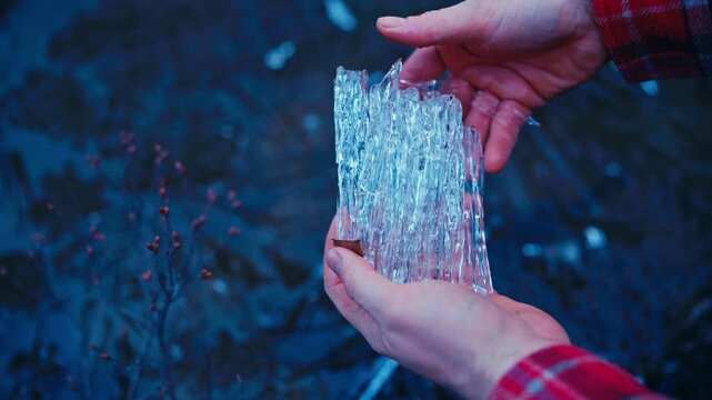 Man holding and breaking crystalline ice, showing detailed ice crystals and fragments as the frozen material breaks apart