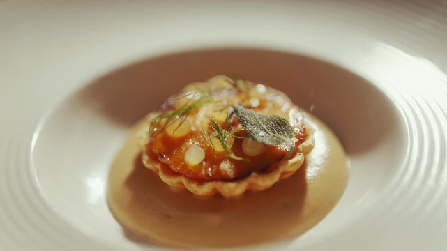 Gourmet tart with tomato sauce and herbs on a white plate