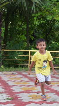 Joyful young boy running outdoors in park with happy expression
