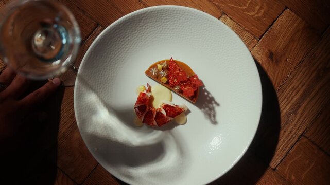 Artistic plating of red fish dish with caviar and a glass of wine