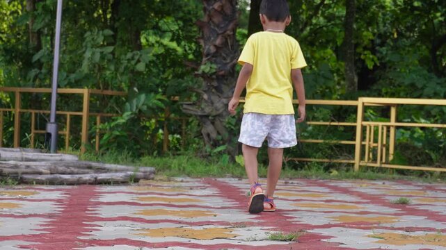Active young boy in yellow graphic t-shirt and shorts walking outdoors
