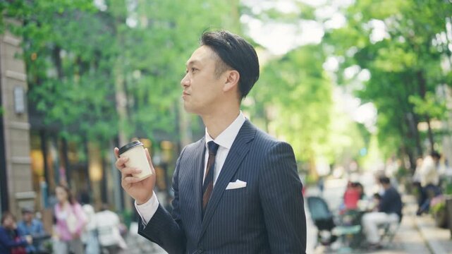 Businessman walking with a takeaway coffee through the office district