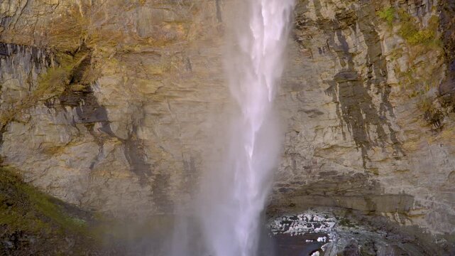 A scenic shot zooming out from the top source to the base of the majestic Sissu Waterfall, featuring powerful water cascading down a rugged rocky cliff in the Himalayan Lahaul Valley.
