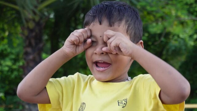 Tired upset child rubbing eyes showing emotional distress