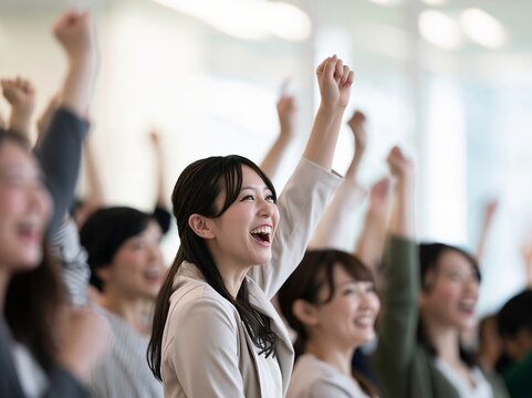 セミナー会場で目標の達成を祝い皆で力強くガッツポーズをして喜ぶ人々