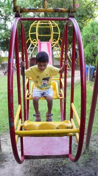 Happy child playing on colorful rotating playground swing