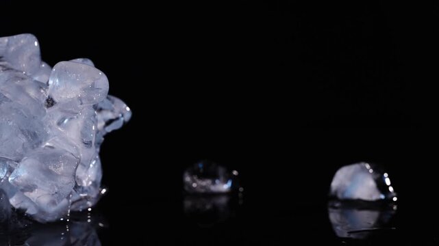 Clear ice pile gliding from the side toward center on black background for drink cooling, refreshment visuals and abstract design