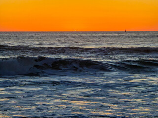 Obraz premium Ocean Waves at Sunset With Sun Disappearing Below Horizon