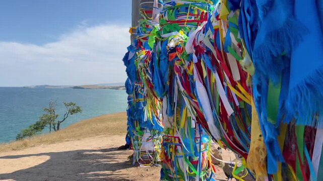 Baikal Lake. Olkhon Island. Video of Serge ritual pillars with blue and colorful ribbons and Hadaks of Buddhists and tourists near Khuzhir village. Popular landmark of Cape Burkhan