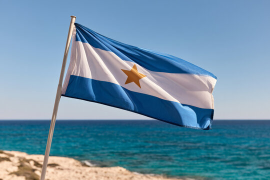 Cyprus national flag waves above a Mediterranean beach. Island identity, national symbol, coastal landscape.