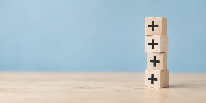 Plus sign in wooden cubes stacking. Positive things; additional, added value, benefits, improve, develop, growth mindset, positive thinking, motivation, increase, opportunities, and emerging market.