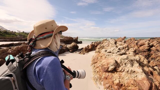 female photographer wearing backpack photographing Kammabaai Beach,  South Africa