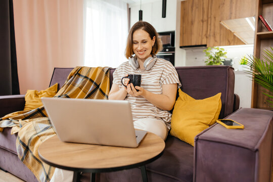 Woman with laptop and coffee relax at home on sofa